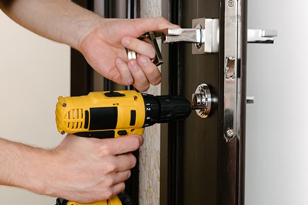 Handwerker montiert mit dem Akkuschrauber einen Beschlag an einer Wohnungstür