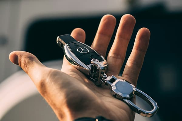 Offene Hand mit einem Autoschlüssel und Schlüsselanhänger