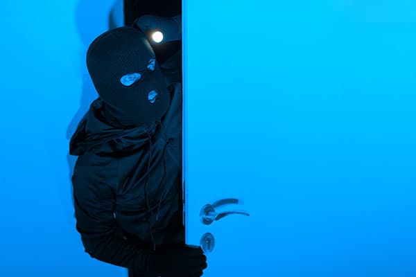 Maskierte Person im blauen Licht an einer Tür