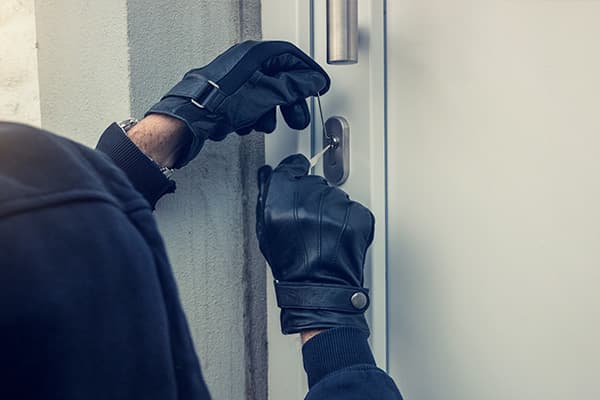 Behandschuhte Hände manipulieren einen Schließzylinder von außen