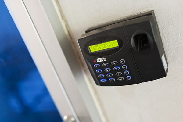 Zutrittsterminal mit Zifferntastatur und Fingerabdruckleser neben einer Tür