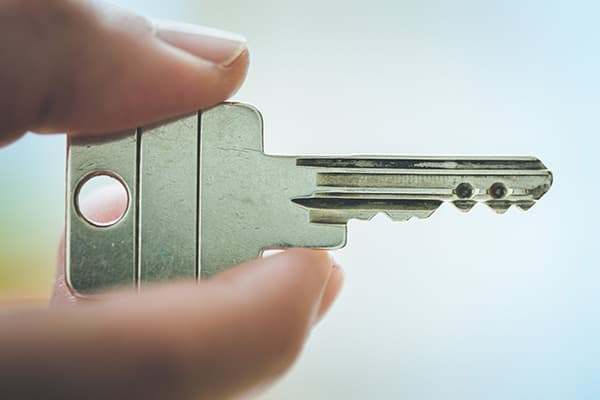Finger halten den Schlüssel einer Schließanlage