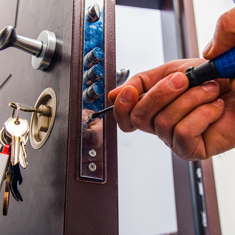 Monteur arbeitet mit dem Schraubendreher am Schloss einer Wohnungstür