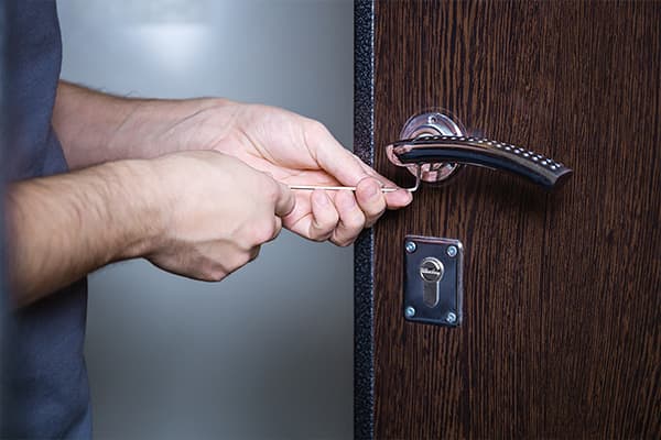 Monteur öffnet eine Wohnungstür mit einem schmalen Werkzeug