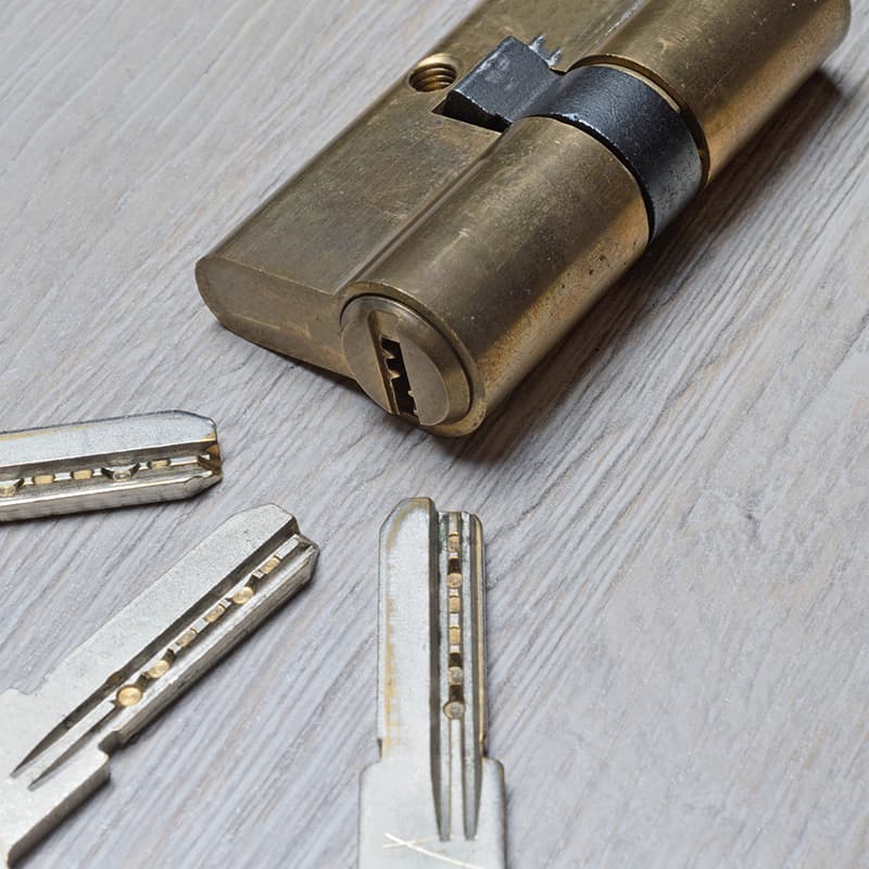 Ausgebauter Profilzylinder mit zwei Schlüsseln auf einer Holzfläche