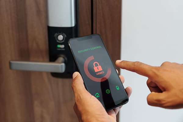 Hand entriegelt eine Tür per Smartphone-App am Smart Lock