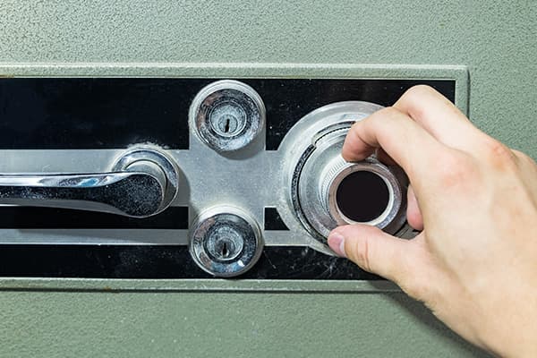 Hand dreht am Kombinationsschloss eines Tresors