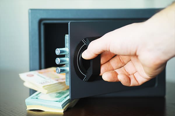 Hand öffnet einen Tresor, in dem Geldscheine liegen