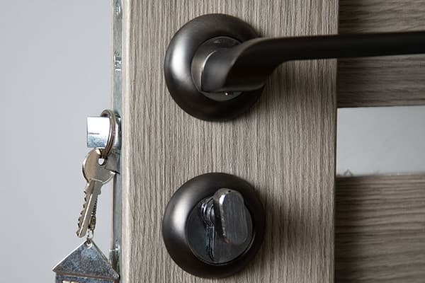 Wohnungstür mit schwarzem Griff, Knaufzylinder und steckendem Schlüsselbund