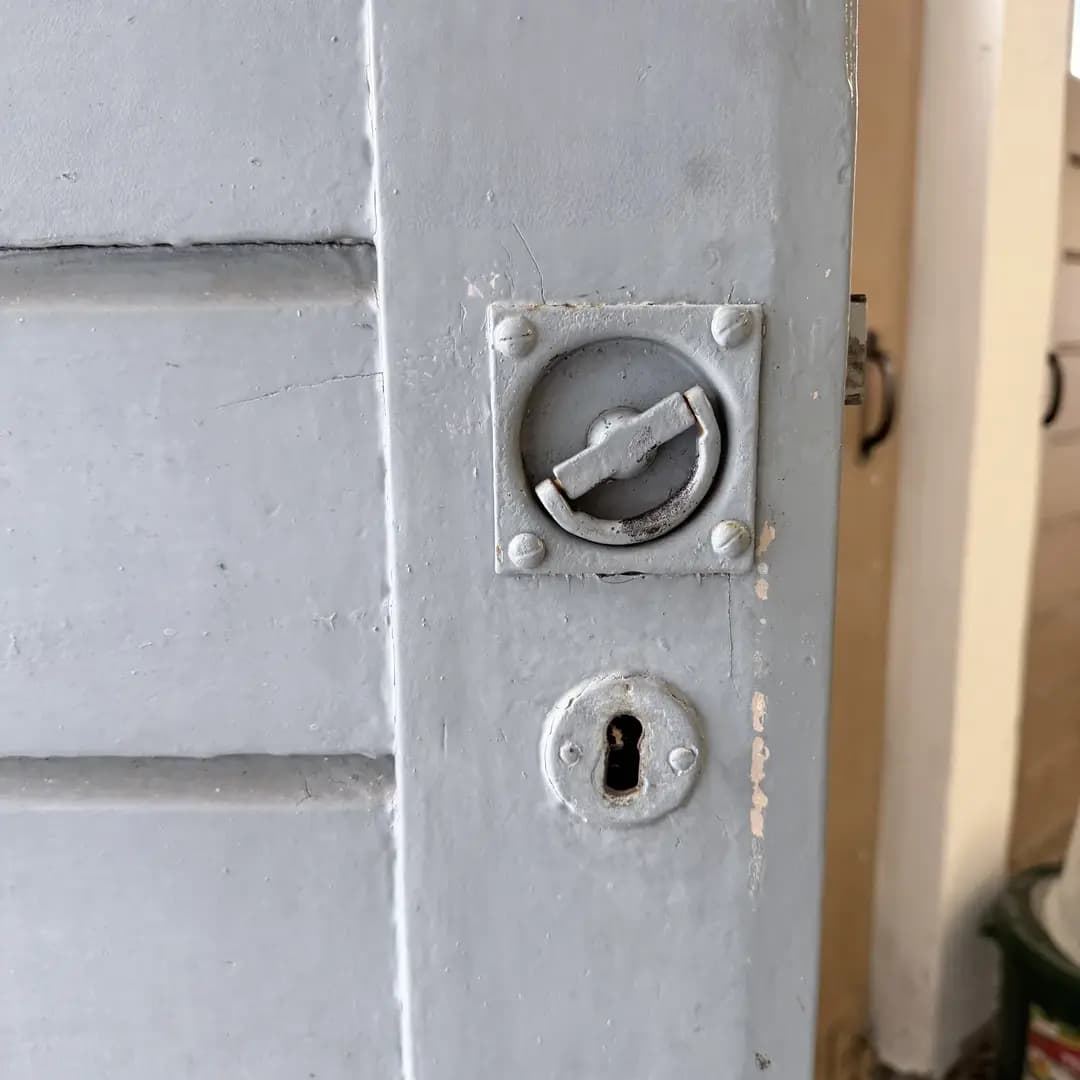 Graue Tür mit altem Schloss und Schlüsselbohrung aus Metall.