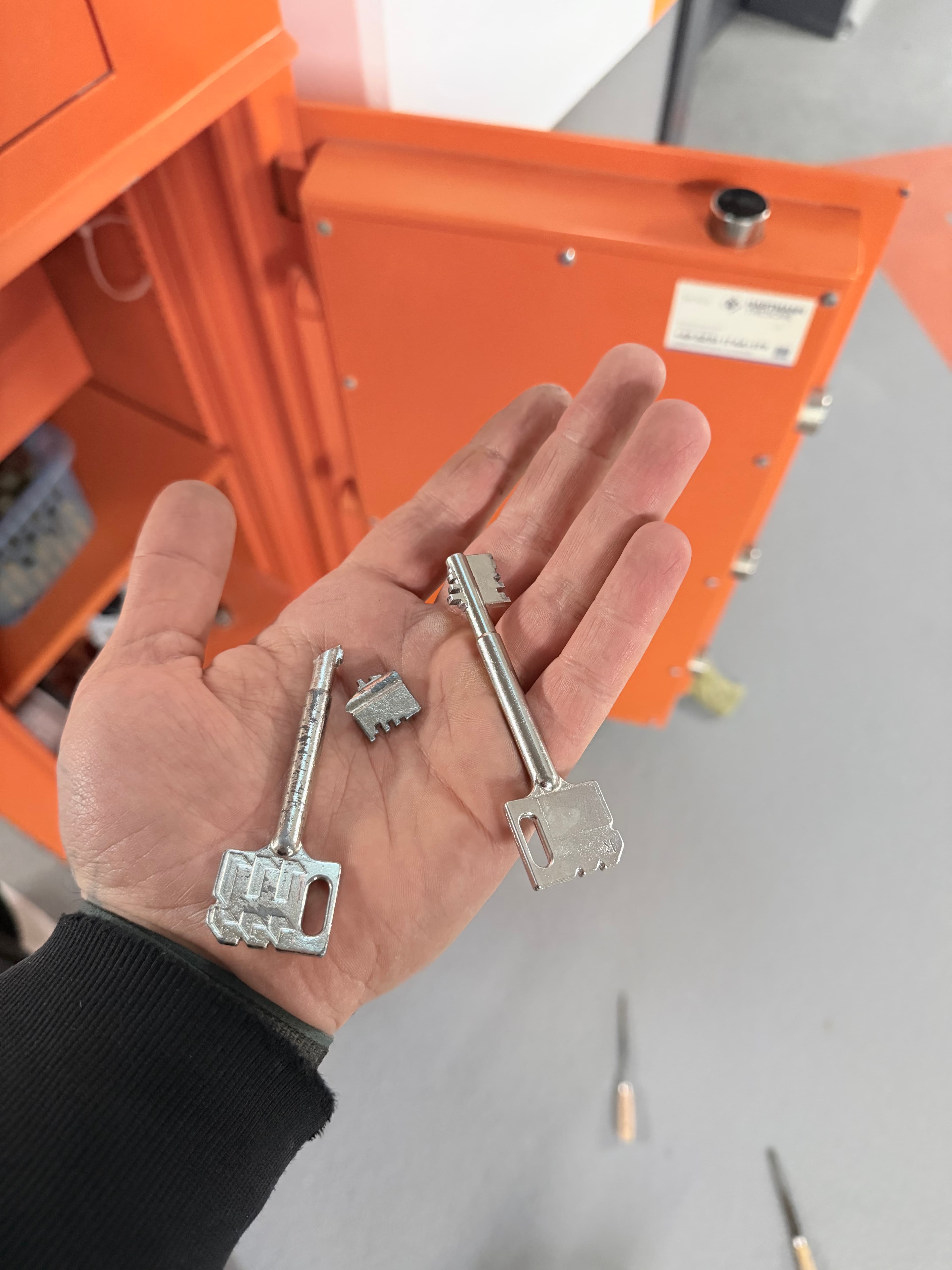 Hand hält einen Doppelbartschlüssel über einem geöffneten Tresor