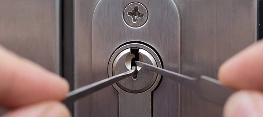 Person öffnet ein Türschloss mit zwei Dietrichen für schadenfreie Türöffnungen.