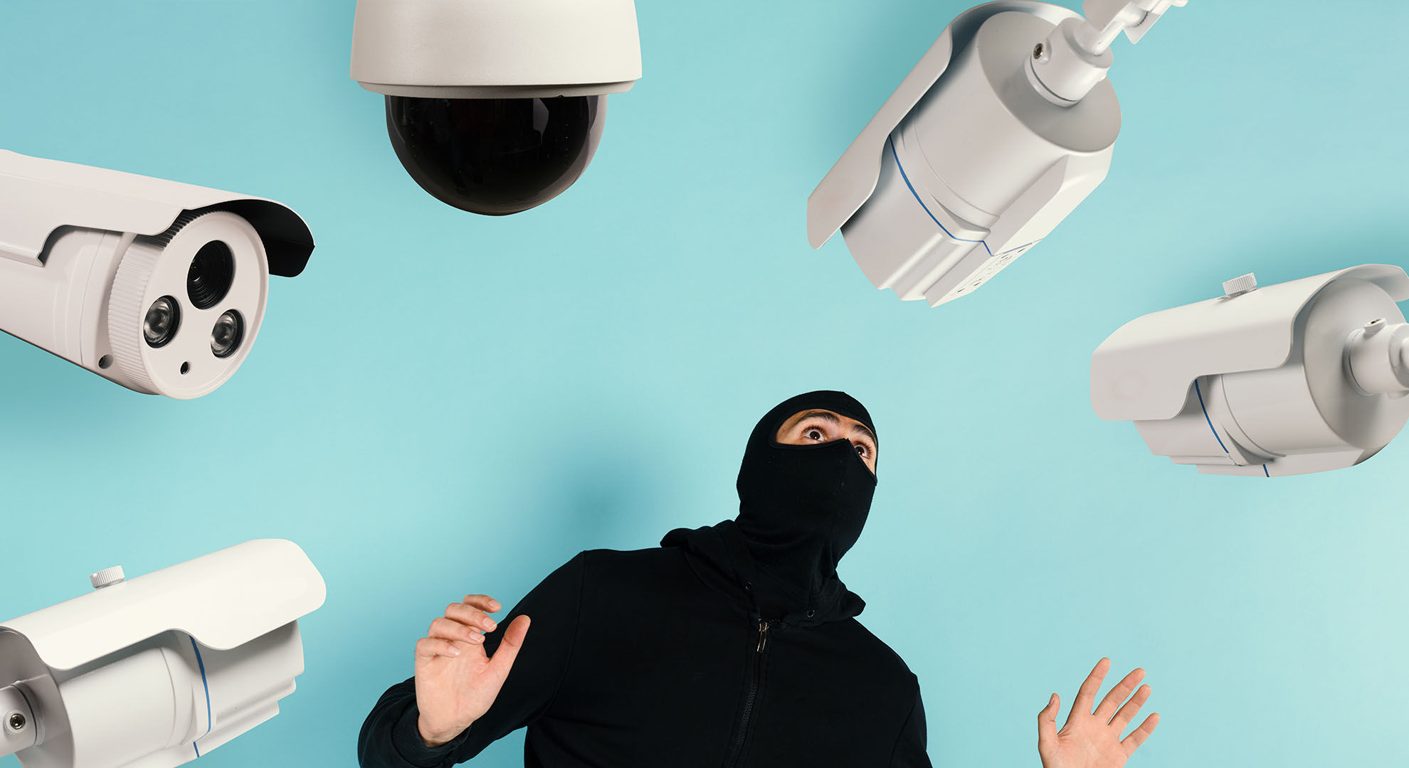 Überwachungskameras und Sensoren rund um einen maskierten Einbrecher