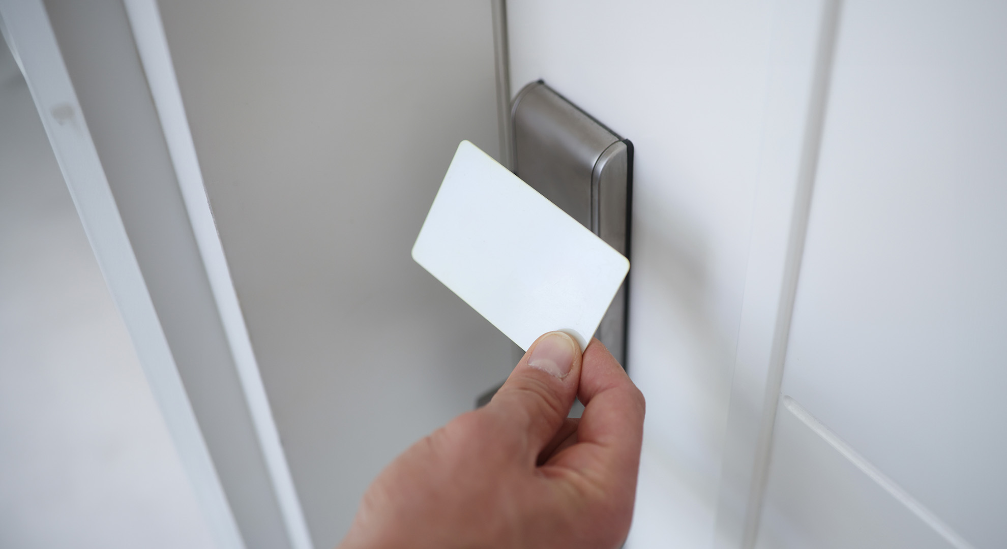 Hand schiebt eine Öffnungskarte in den Türspalt