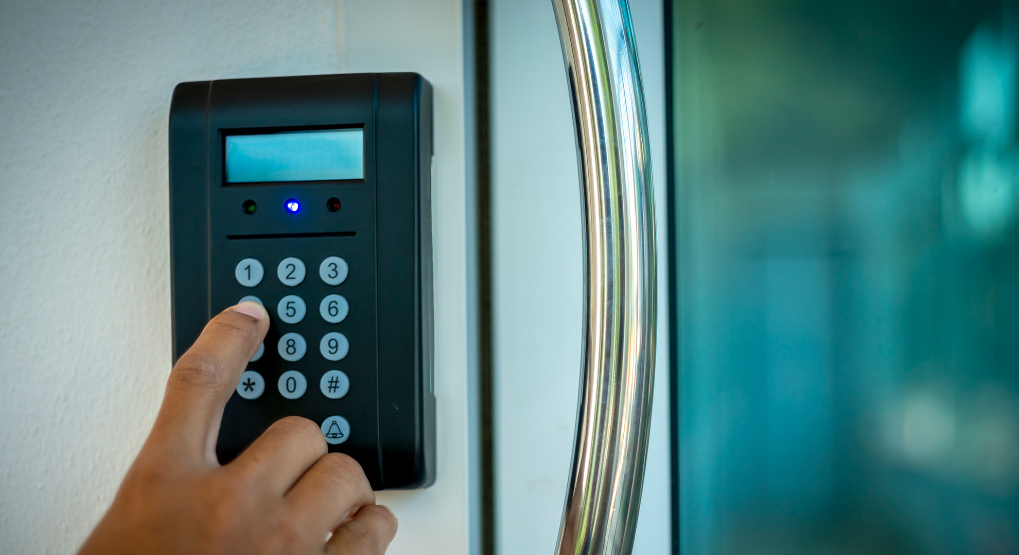 Person gibt einen Code an einem Zutrittsterminal neben einer Glastür ein