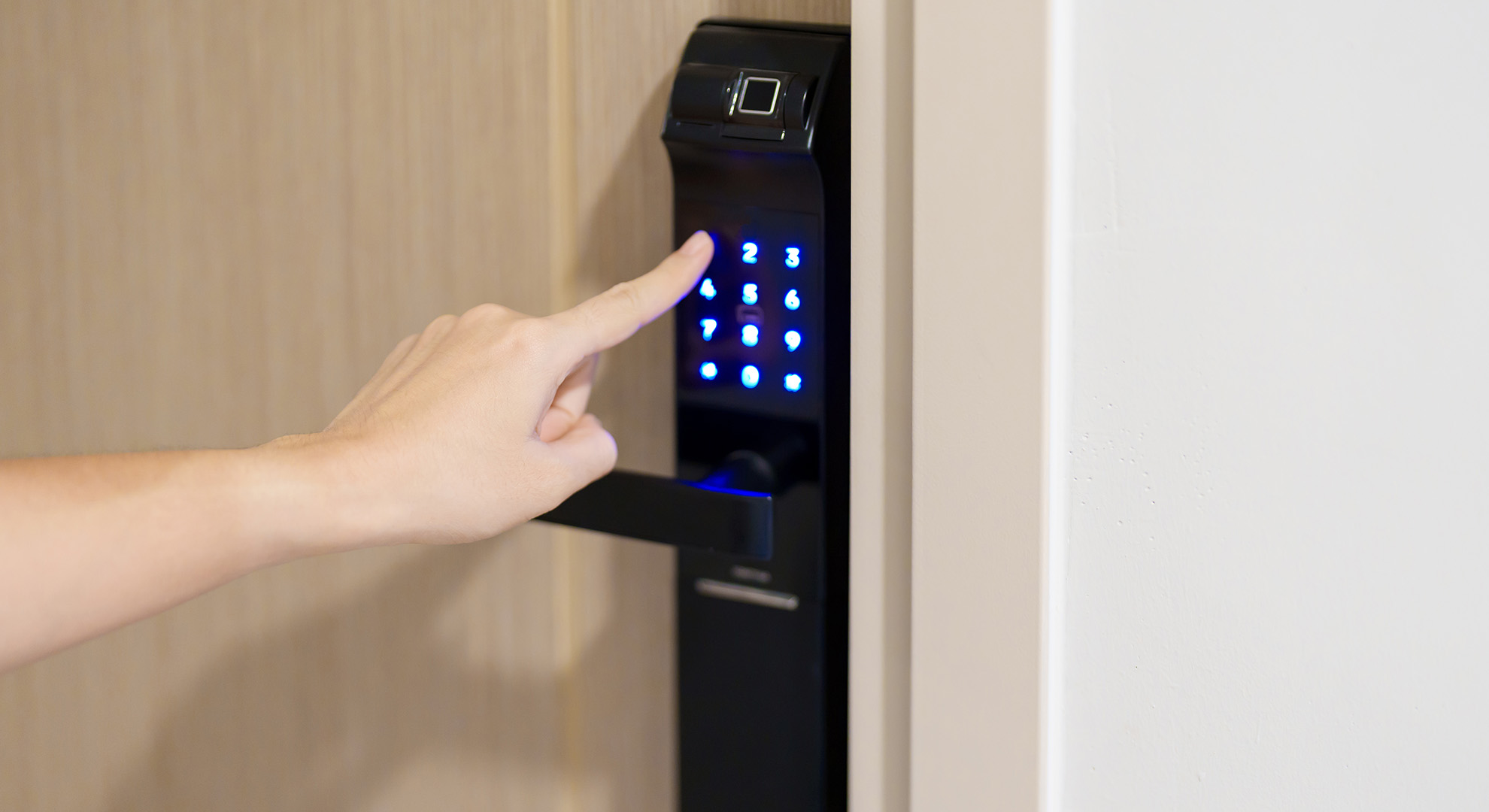 Finger bedient einen elektronischen Türöffner mit Zahlenfeld